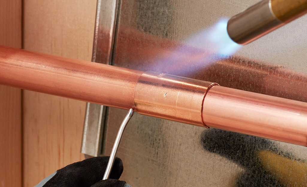 Copper pipe soldering process using torch and solder for plumbing HVAC systems